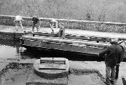 Having been t ransported by water the 1 miles from Cromford, the galvanised sections arrive on our workboat. In the foreground is the completed main bearing assembly on the main concrete base. (The rest was filled later).