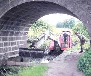 The Smith 14 excavator approaches Bridge 1, with Simon Stoker driving and Toby Banks assisting. (ADS)