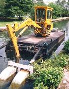 The original long-reach Smalley excavator was converted to a floating dredger by the manufacturer. This was a very effective aid to clearing the canal. The pontoon had to be made narrower than their standard 6ft 10in in order to get into the drydock and through the Gregory Tunnel.