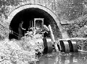 The dredger emerges from theGregory Tunnel into Gregory Dam. The considerable accumulation of rubbish in the mouth of the tunnel has made the machine ride up on its wheels.