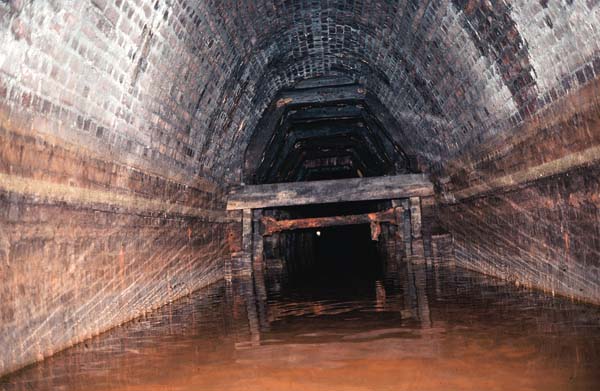 From the same point looking along the tunnel. Low cross wooden supports sloping left.