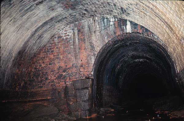 West end of wide hole, narrowing to normal tunnel width; silt, dressed stones.
