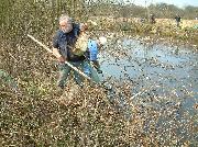 Fishing waste out of the lock pounds using the traditional tool of a hook on a stick!